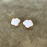 Pair of gold and white floral earrings on a concrete surface
